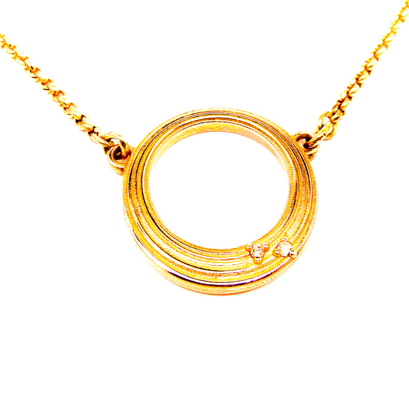 Een hanger, rond van vorm en open als een ring als symbool voor de liefde voor haar 2 kinderen die worden weergegeven met 2 gelijke diamantjes aan de kant van het hart.
