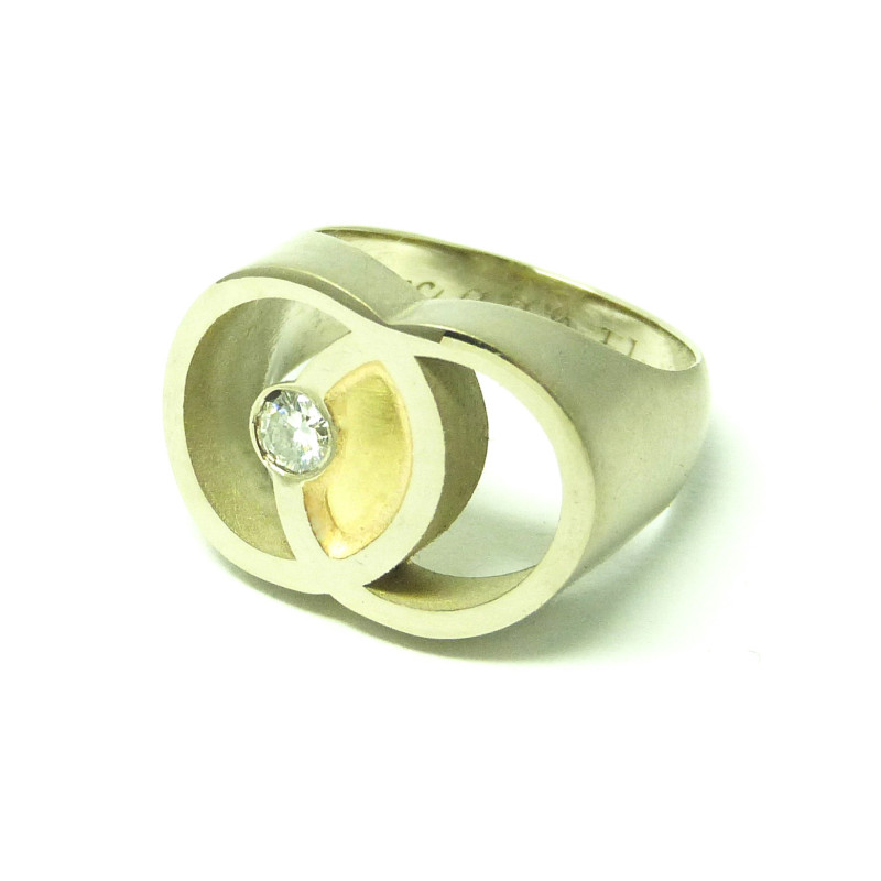 Palladium Wit Gouden RouwRing met 2 overlappende cirkels, het symbool Vesica Piscis. In het overlappende gedeelte, de Mandorla, zit de As onder een Geel Gouden amandelvormig plaatje. Asymmetrisch een Diamant die zij kreeg van haar man.